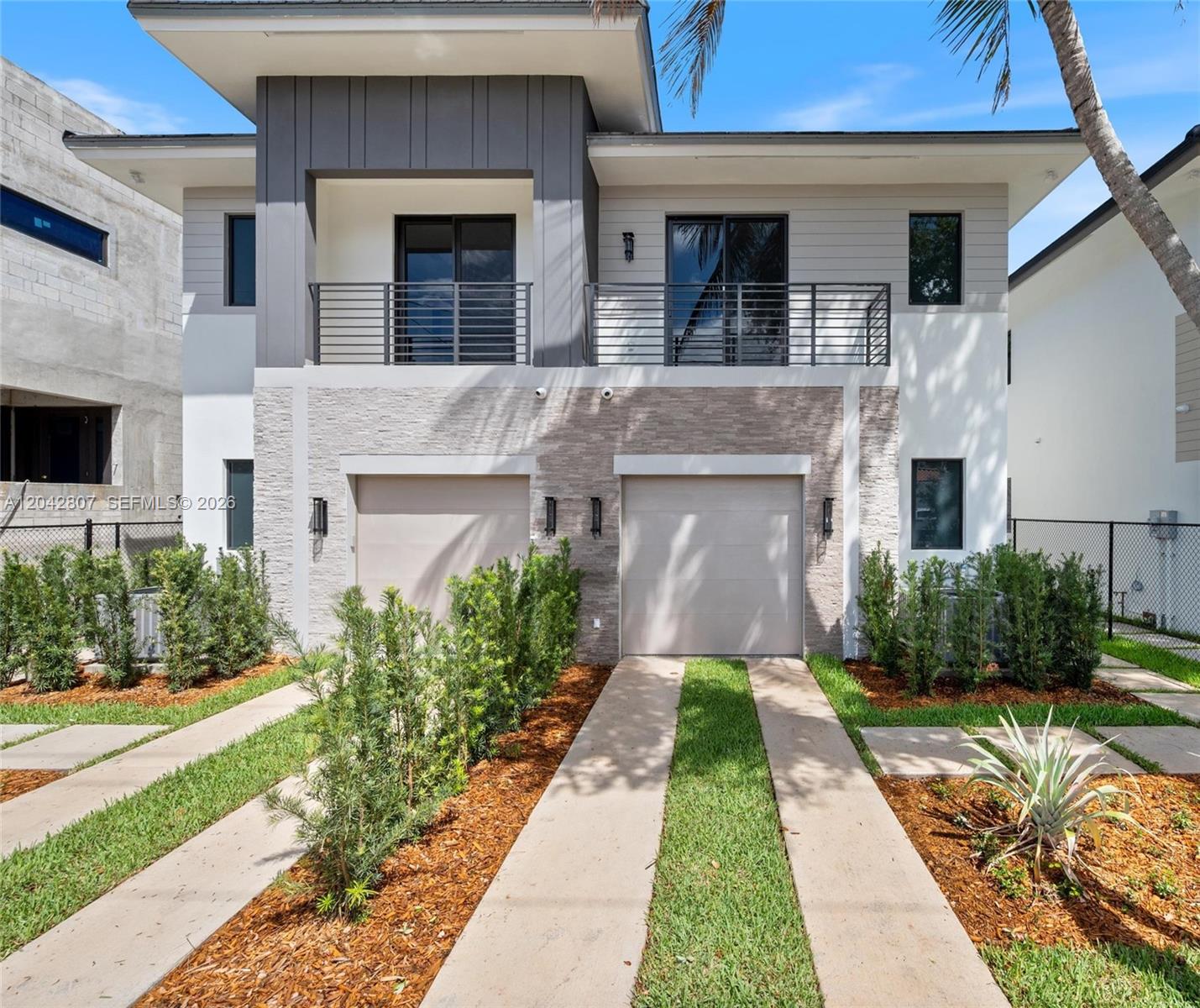 A two-story modern duplex features two garages, stone veneer, and upper-level balconies — 2747 SW 23rd Ter, Miami FL 33145, MIAMI, FL
