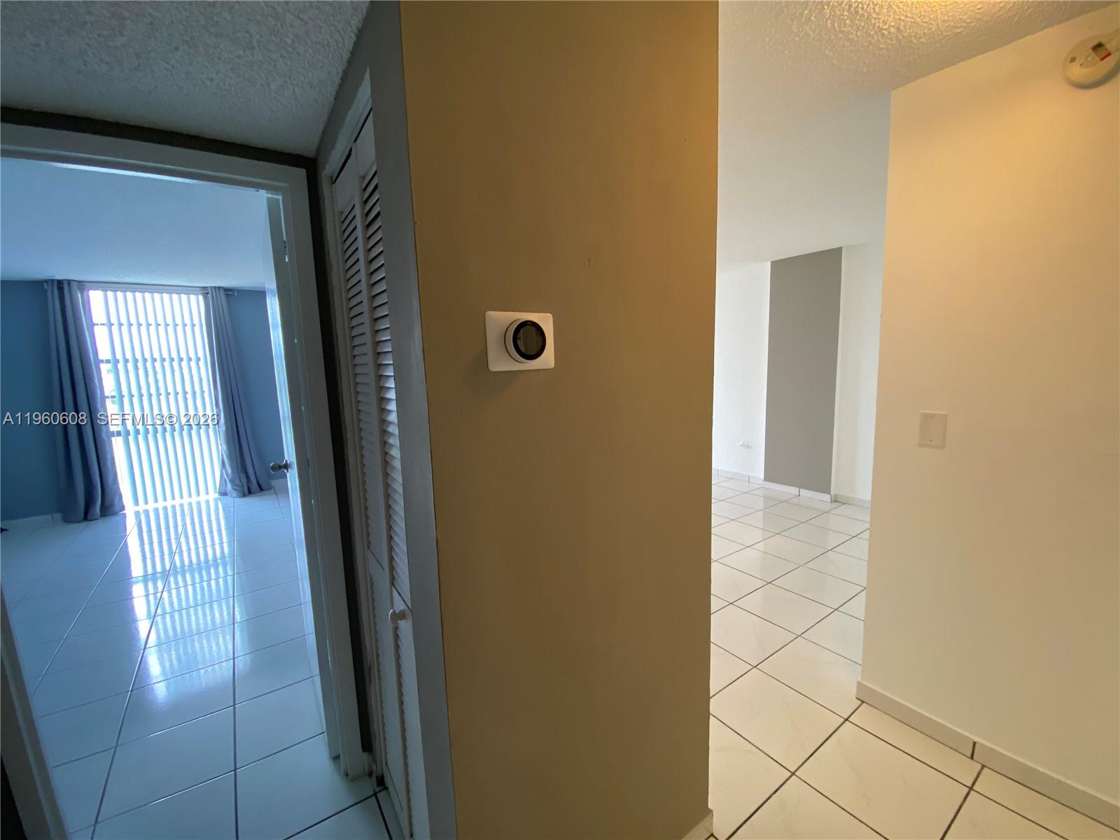 A hallway with white tile flooring leads to a room with blue curtains and blinds — 16950 DIXIE # A536, North Miami Beach FL 33160, NORTH MIAMI BEACH, FL