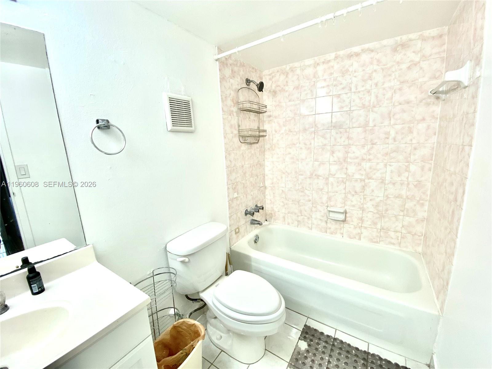This bathroom features a white vanity, a toilet, and a bathtub with pink-tiled walls — 16950 DIXIE # A536, North Miami Beach FL 33160, NORTH MIAMI BEACH, FL