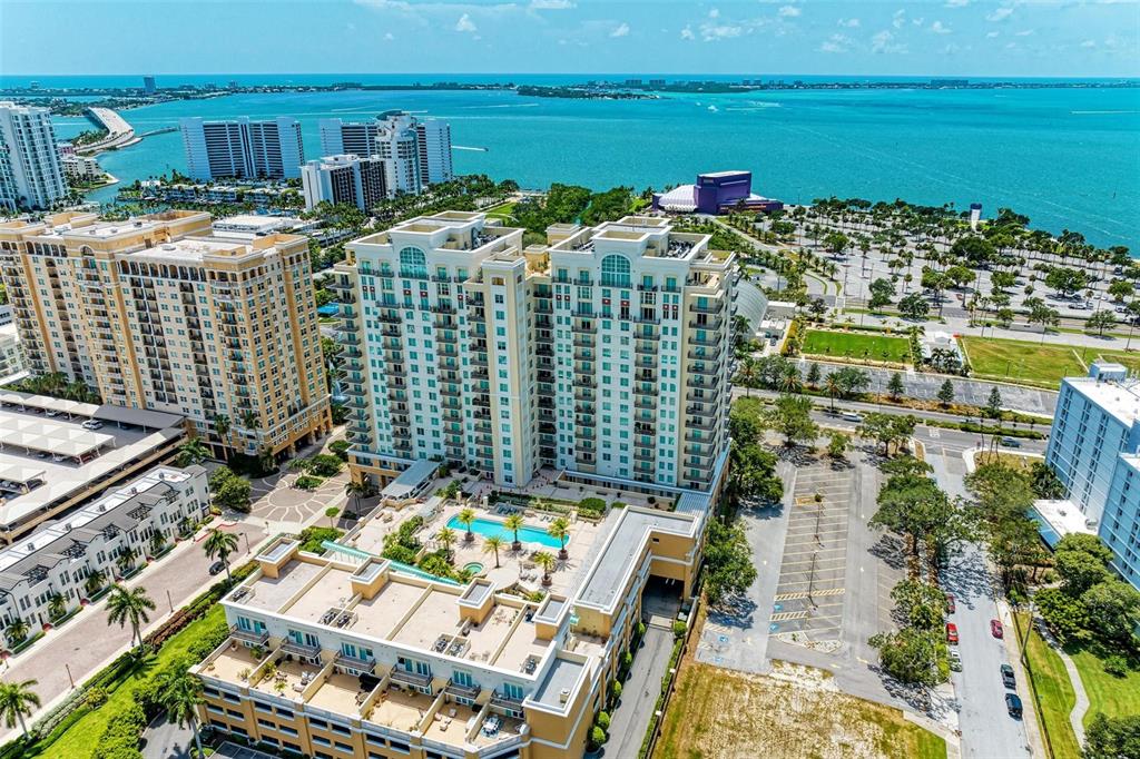 An aerial view shows a multi-story residential complex with a pool deck and nearby water — 800 N TAMIAMI TRAIL UNIT 212, SARASOTA, FL