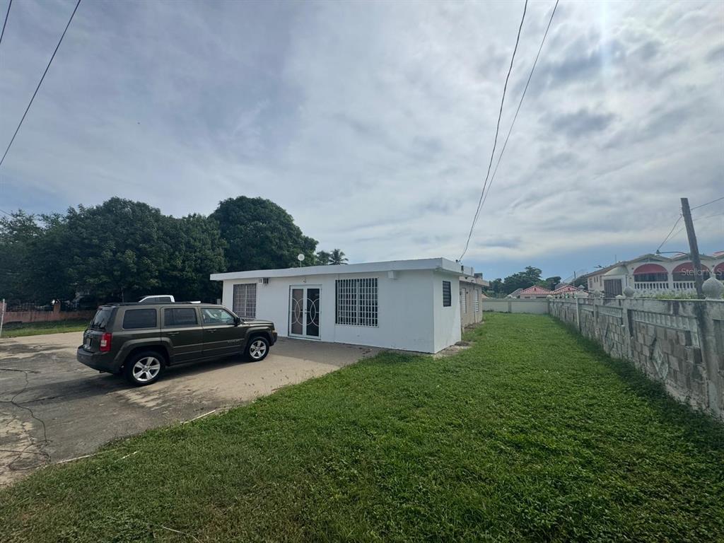A white single-story house with a paved driveway and a green lawn — 690 St. BO. SABANA, VEGA ALTA, PR