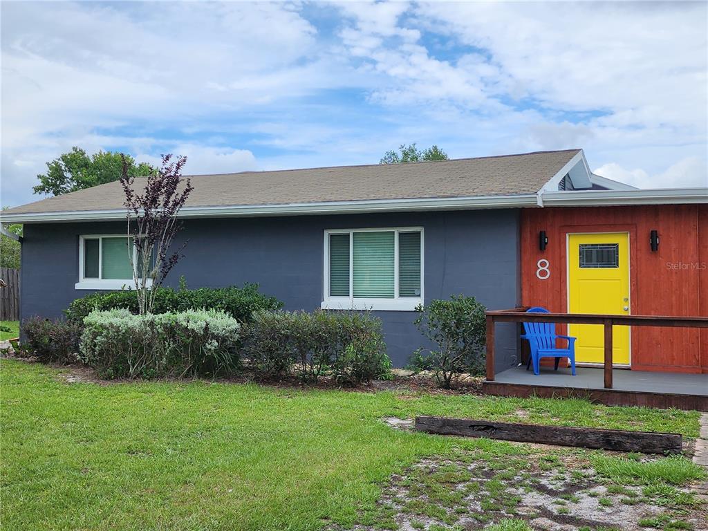 A gray house with a bright yellow front door and a wooden porch — 8 POINSETTIA DRIVE, DEBARY, FL