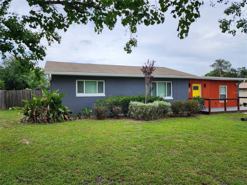 A single-story house with gray and wood-paneled siding, a yellow door, and a front lawn — 8 POINSETTIA DRIVE, DEBARY, FL