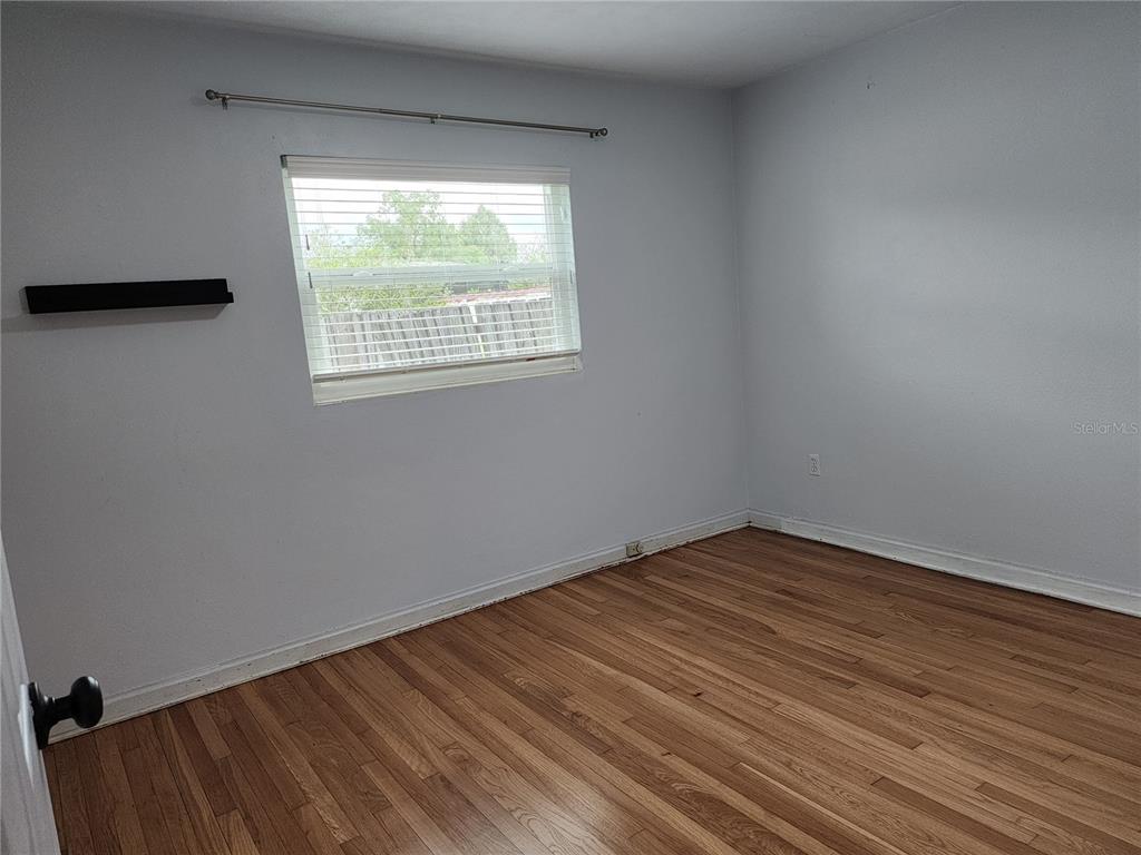 An empty bedroom features light gray walls, hardwood flooring, and a single window with blinds — 8 POINSETTIA DRIVE, DEBARY, FL
