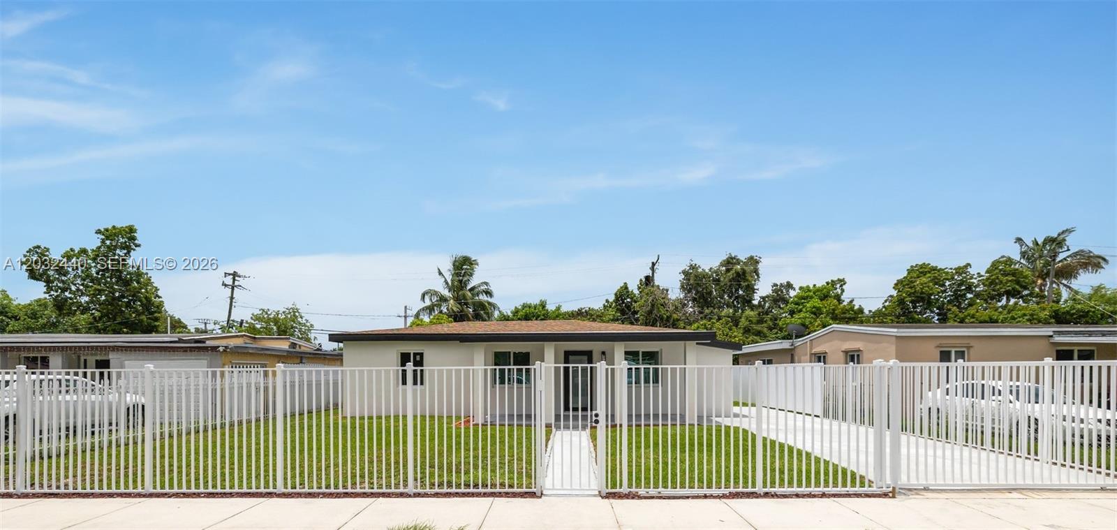 A single-story house with a white fence, green lawn, and a concrete driveway — 3260 NW 95th Ter, Miami FL 33147, MIAMI, FL