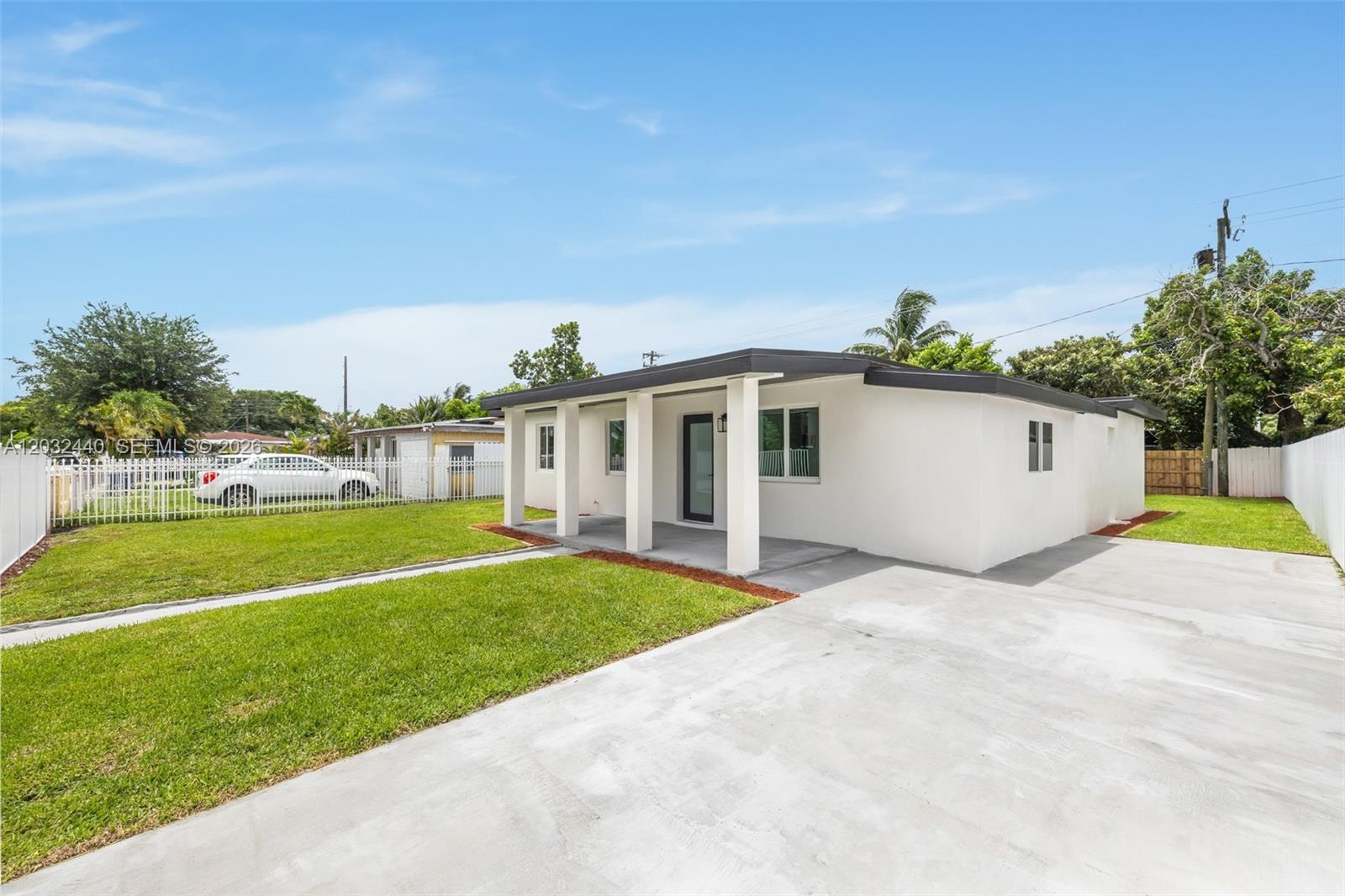 A white, single-story house features a covered front porch, concrete driveway, and a fenced yard — 3260 NW 95th Ter, Miami FL 33147, MIAMI, FL