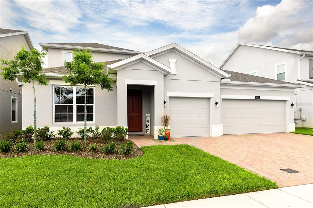 A single-story suburban house with a gray exterior, a two-car garage, and a brick driveway — 5012 BESSIE COURT, ST CLOUD, FL