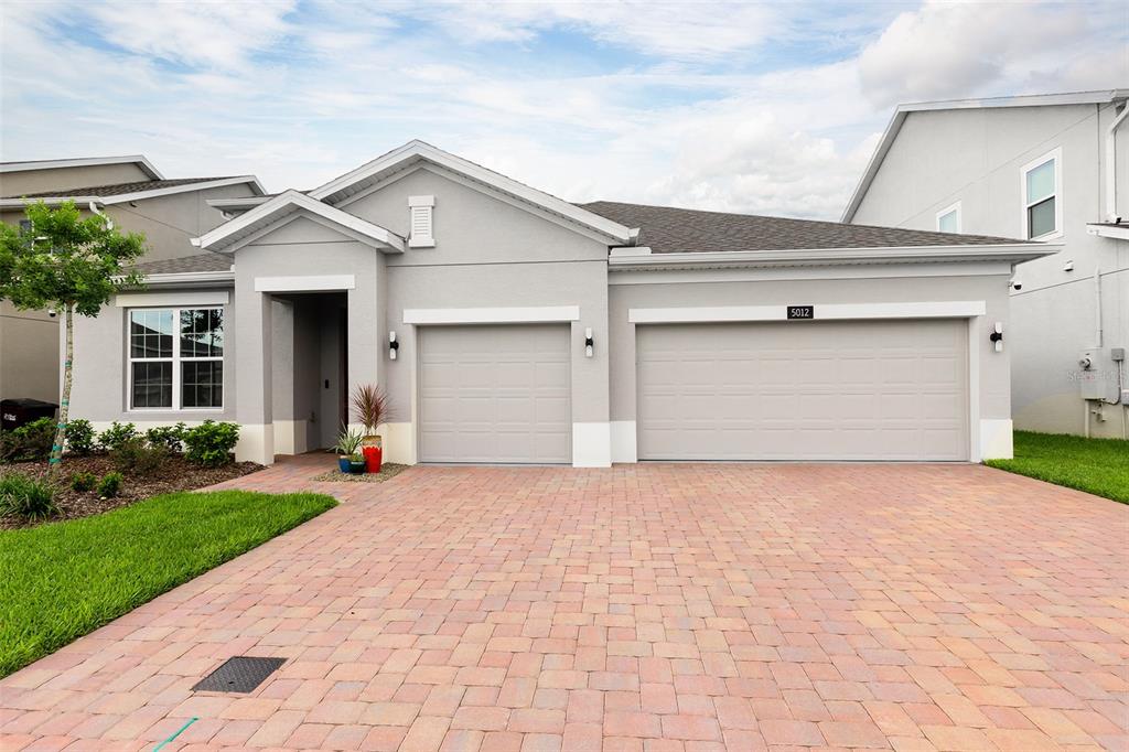 A gray single-story house with a three-car garage and a paved driveway — 5012 BESSIE COURT, ST CLOUD, FL