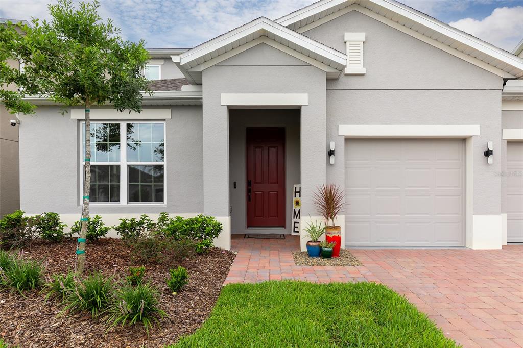 A single-story house with a gray stucco exterior, a red front door, and a paved driveway — 5012 BESSIE COURT, ST CLOUD, FL