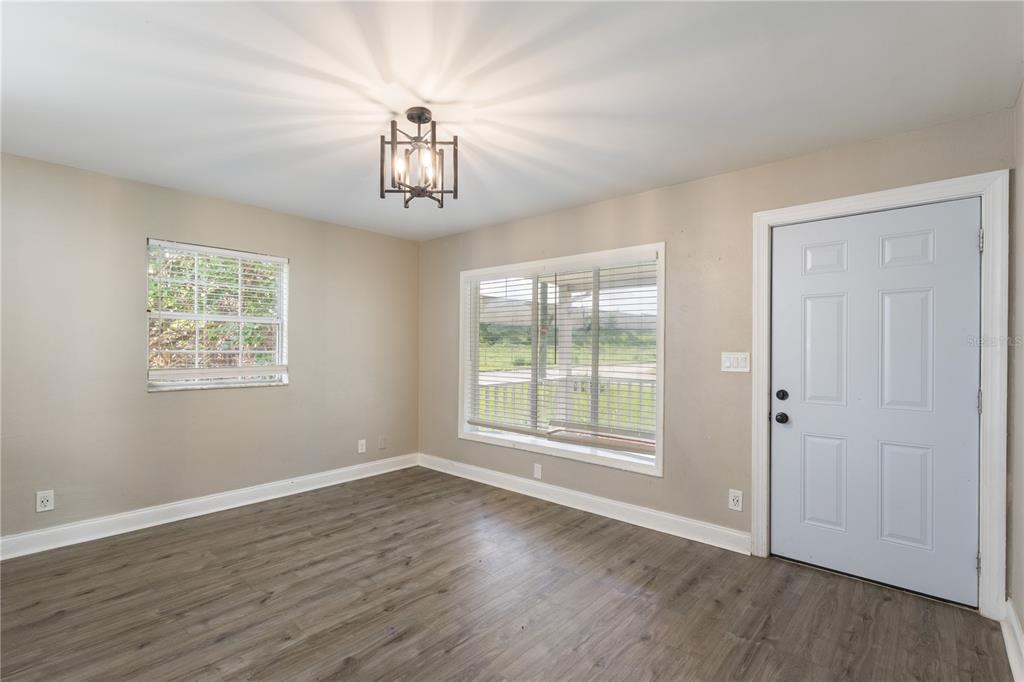 An empty room features light-colored walls, wood-look flooring, a ceiling light fixture, and a door — 320 E ALTHEA AVENUE, TAMPA, FL