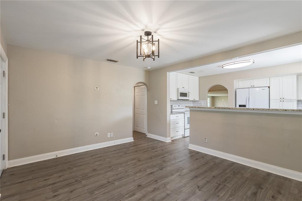 An open-concept dining area features wood-look flooring, a modern light fixture, and a kitchen pass-through — 320 E ALTHEA AVENUE, TAMPA, FL