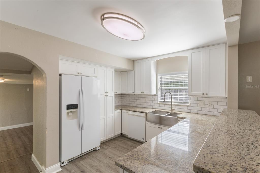 A kitchen with white cabinets, granite countertops, a farmhouse sink, and a white refrigerator — 320 E ALTHEA AVENUE, TAMPA, FL