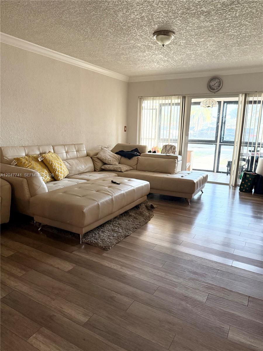 A living room features a large beige sectional sofa, wood-look flooring, and sliding glass doors — 120 Lakeview Dr # 114, Weston FL 33326, WESTON, FL