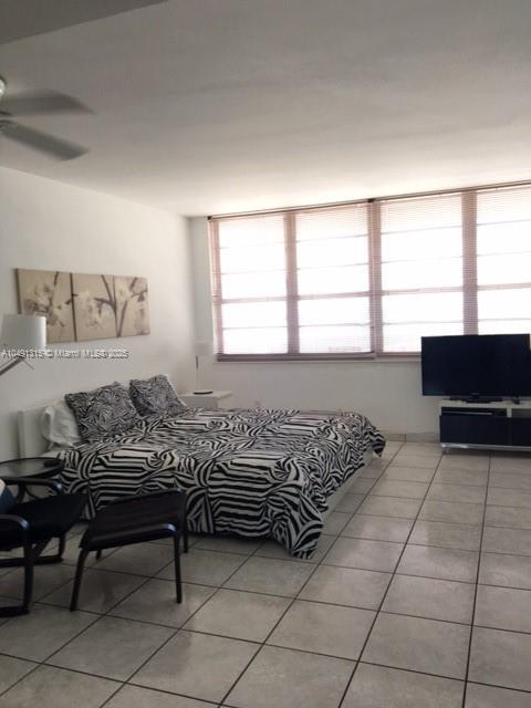 A bedroom features a zebra-print bedspread, tile flooring, and a large window with blinds — 100 LINCOLN RD # 1236, Miami Beach FL 33139, MIAMI BEACH, FL