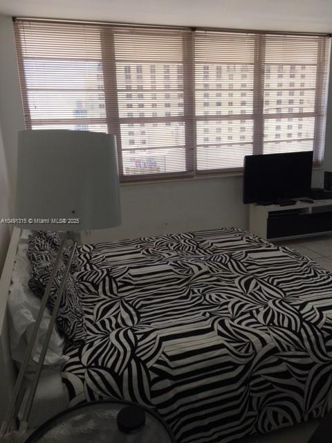 A bedroom features a bed with a black and white patterned comforter and window blinds — 100 LINCOLN RD # 1236, Miami Beach FL 33139, MIAMI BEACH, FL