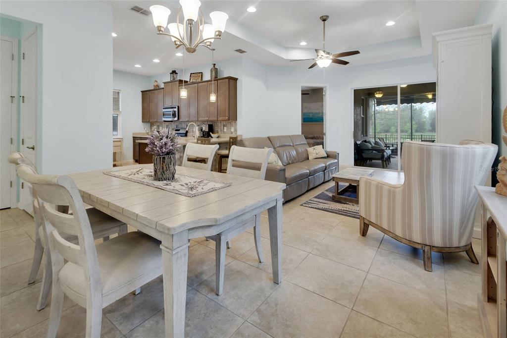 An open-concept living and dining area features light tile flooring, a kitchen, and sliding doors — 412 TISBURY COURT, DELAND, FL