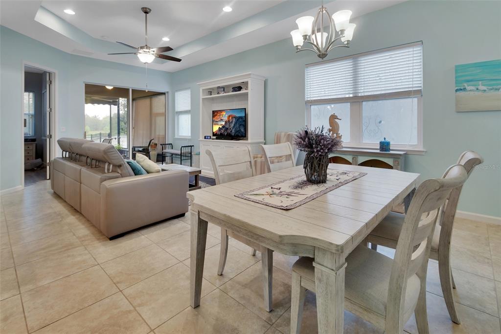 A dining area with a light wood table sits adjacent to a living room — 412 TISBURY COURT, DELAND, FL