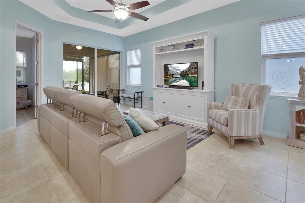 A living room features light blue walls, tile flooring, a white entertainment center, and furniture — 412 TISBURY COURT, DELAND, FL