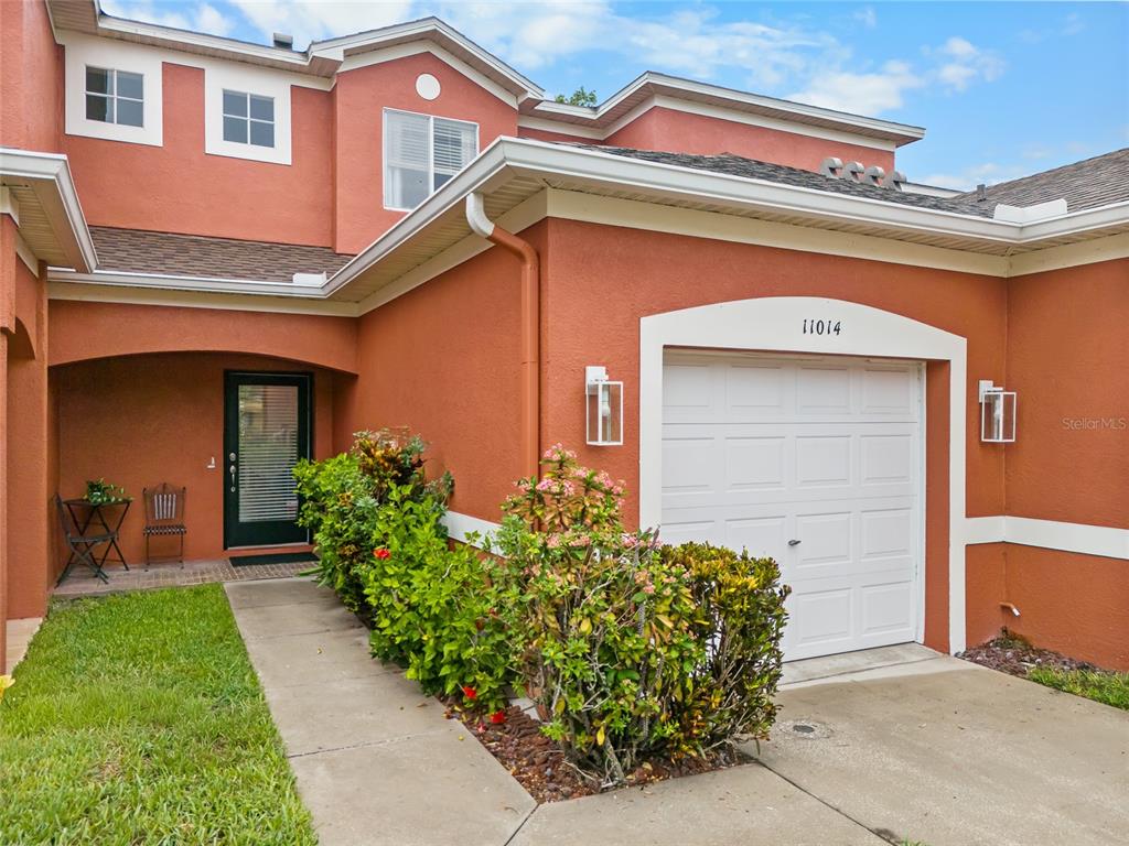 The exterior of a two-story stucco home features a single-car garage and a front walkway — 11014 BLAINE TOP PLACE, TAMPA, FL