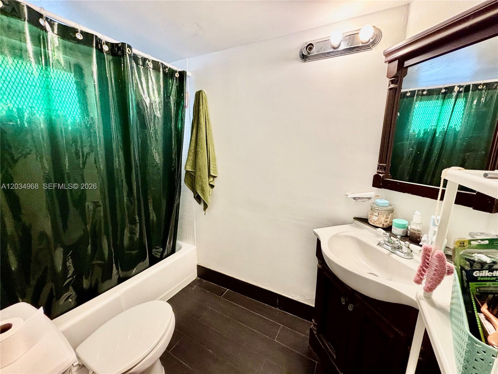 A bathroom features a dark vanity, a white toilet, and a green shower curtain — 1304 NE 191st St # A232, Miami FL 33179, MIAMI, FL