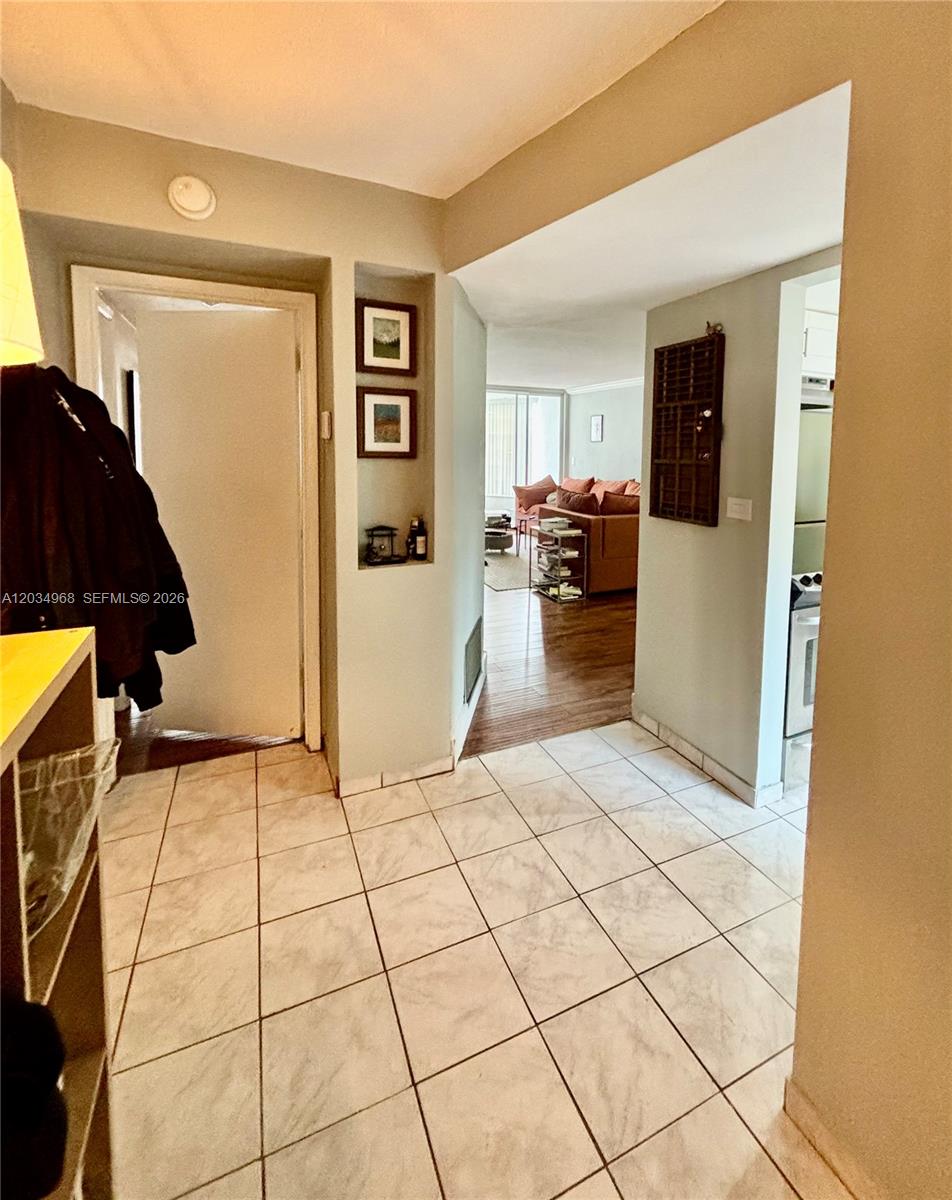 A tiled entryway leads to a living area with wood flooring and a kitchen — 1304 NE 191st St # A232, Miami FL 33179, MIAMI, FL