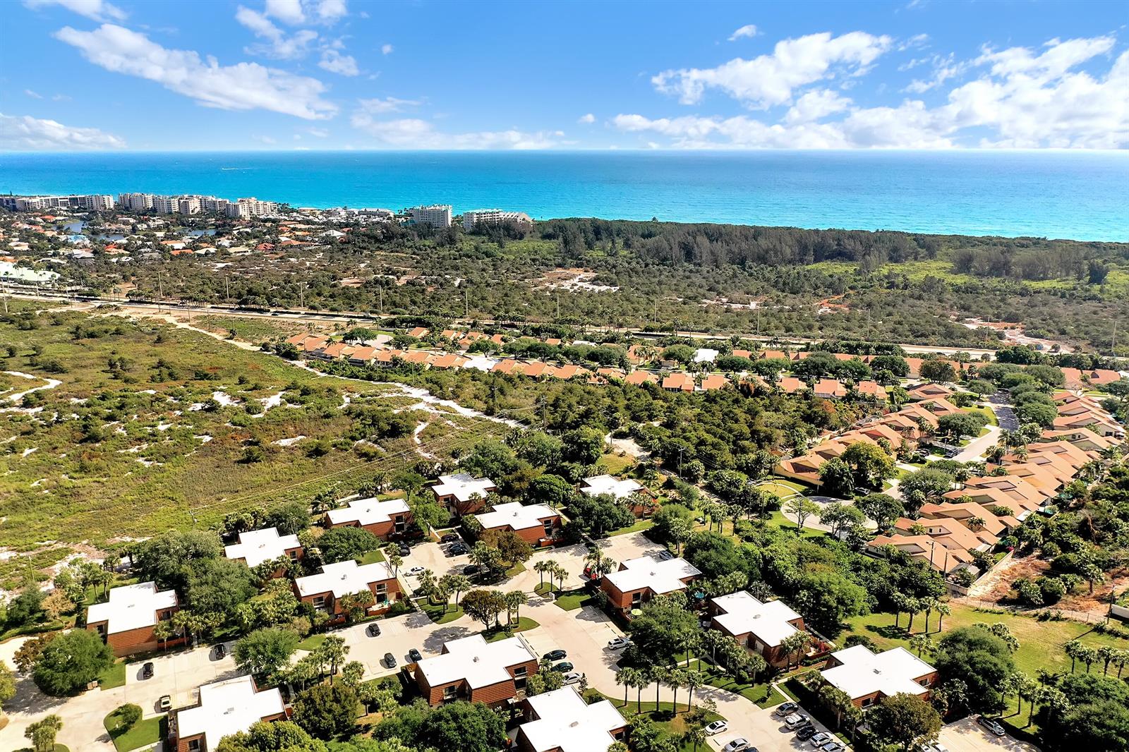 An aerial view shows a residential neighborhood with low-rise buildings surrounded by trees and vegetation — 2715 27th Court, Jupiter FL 33477, JUPITER, FL