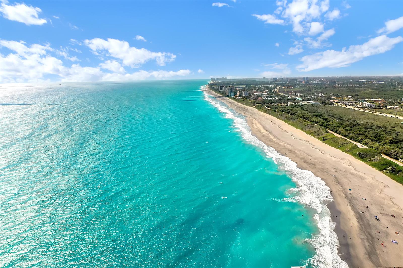 An aerial view shows a turquoise ocean meeting a sandy beach with coastal vegetation — 2715 27th Court, Jupiter FL 33477, JUPITER, FL