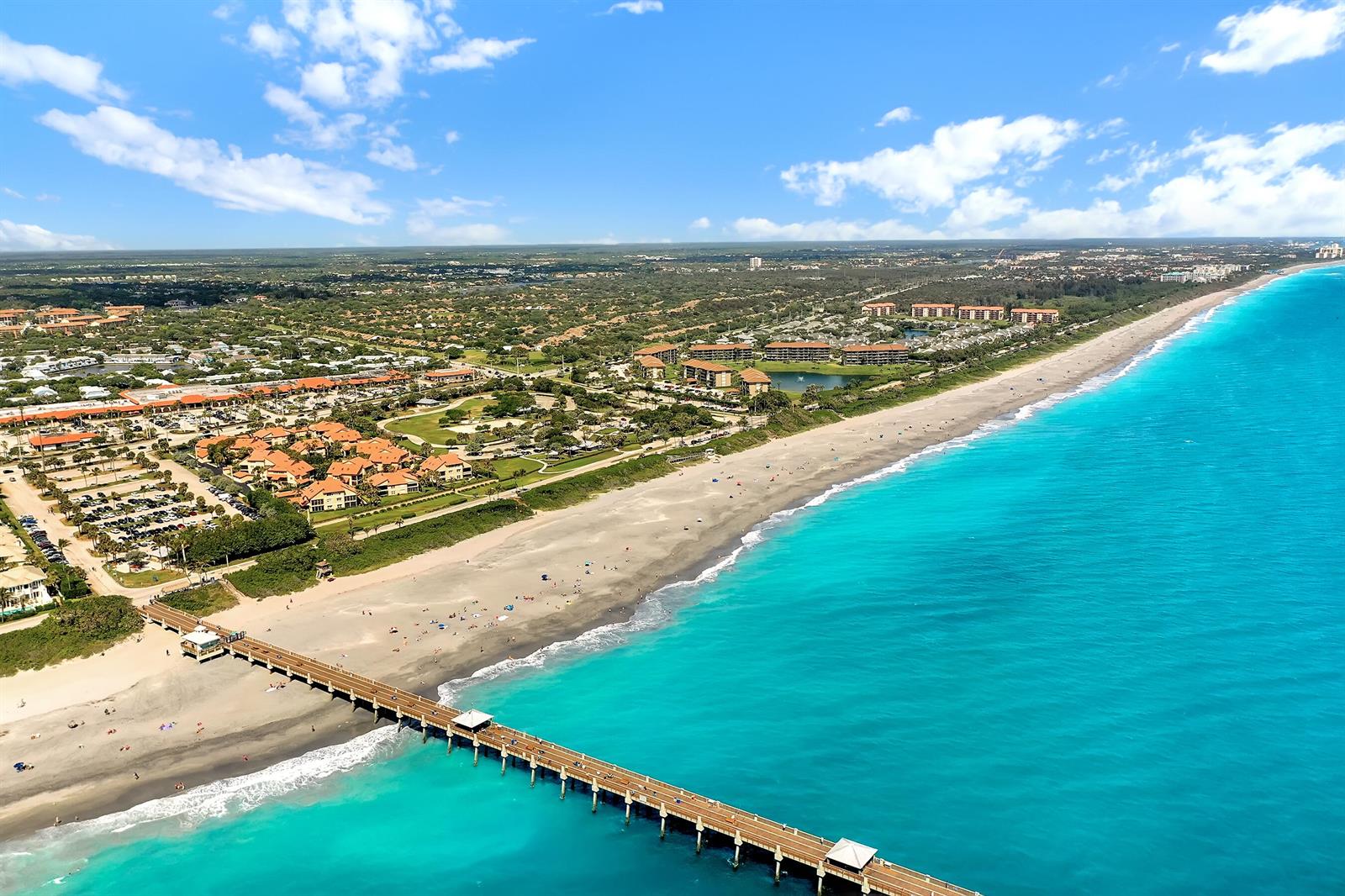 An aerial view shows a long fishing pier extending into turquoise ocean water near a beach — 2715 27th Court, Jupiter FL 33477, JUPITER, FL