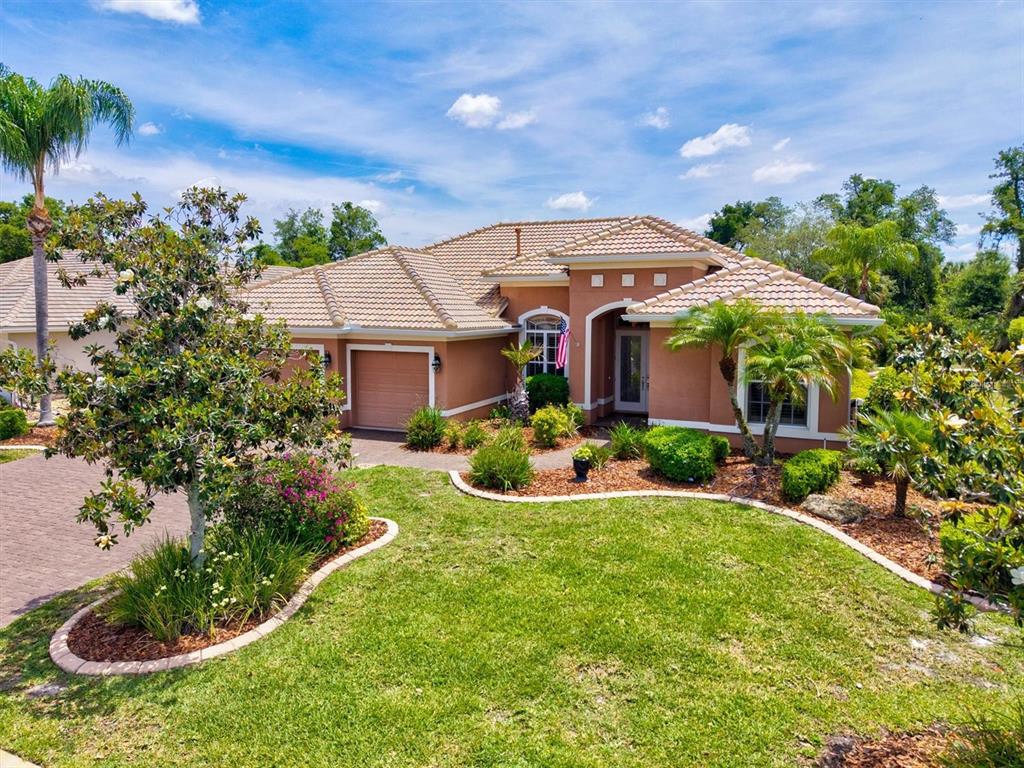 A lit swimming pool with a raised tiled spa sits inside a screened-in patio enclosure — 315 PETREL TRAIL, BRADENTON, FL