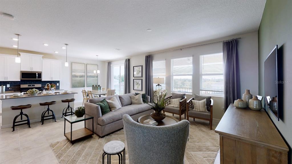 An open-concept living room and kitchen feature tile floors, neutral furniture, and large windows — 5620 FIONA LANE, ST CLOUD, FL