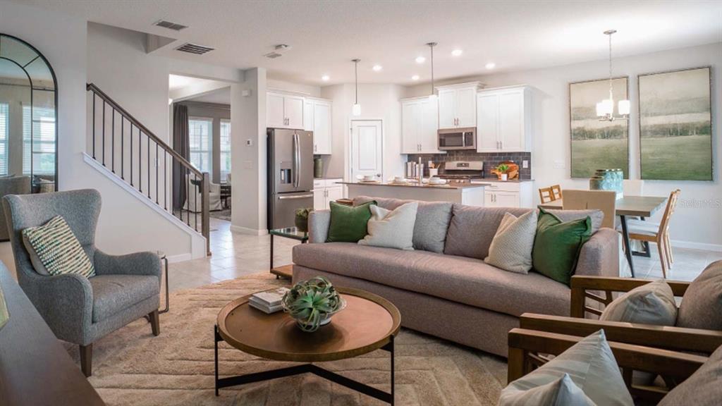 An open-concept living room features a grey sofa, a round coffee table, and a kitchen — 5620 FIONA LANE, ST CLOUD, FL