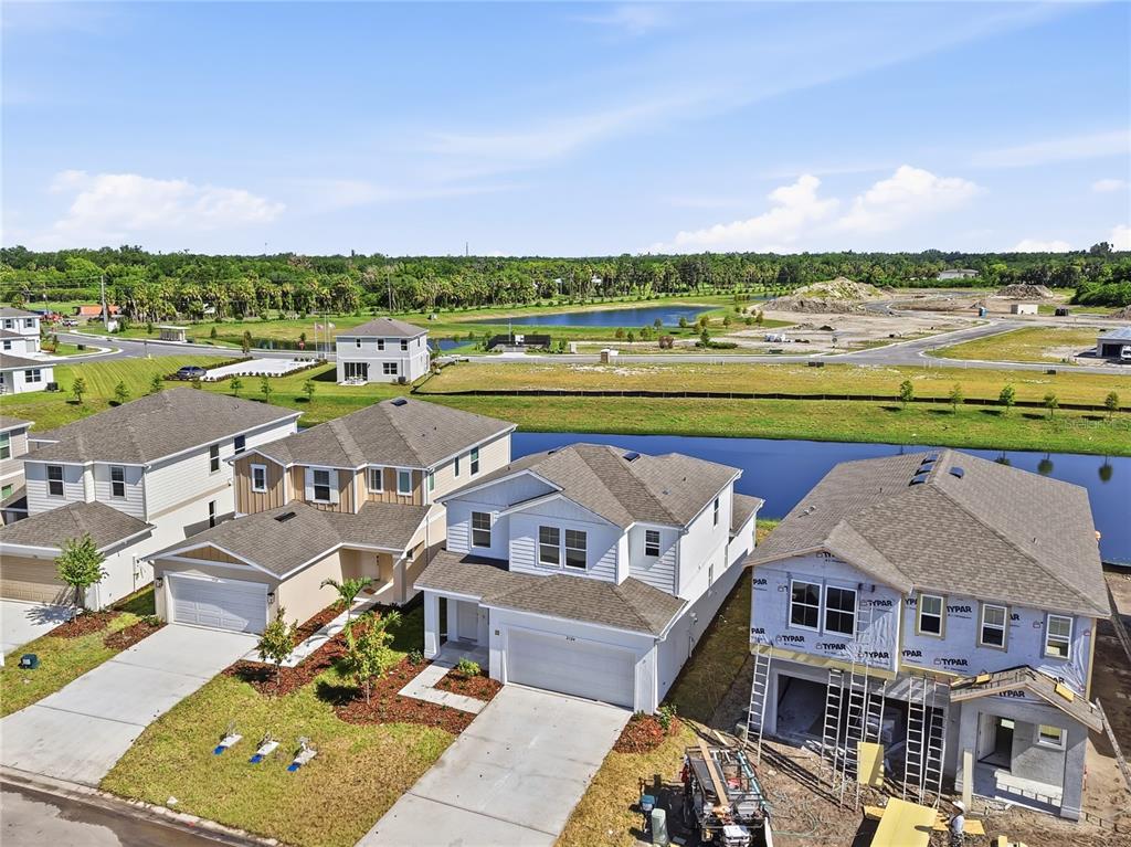 An aerial view shows several suburban houses, including one under construction, near a small pond — 2524 29TH LANE E, PALMETTO, FL