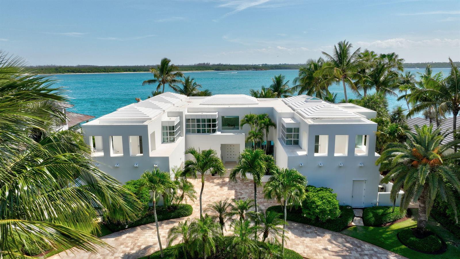 An aerial view of a white two-story waterfront house with a paved circular driveway — 7034 SE Harbor Circle, Stuart FL 34996, STUART, FL