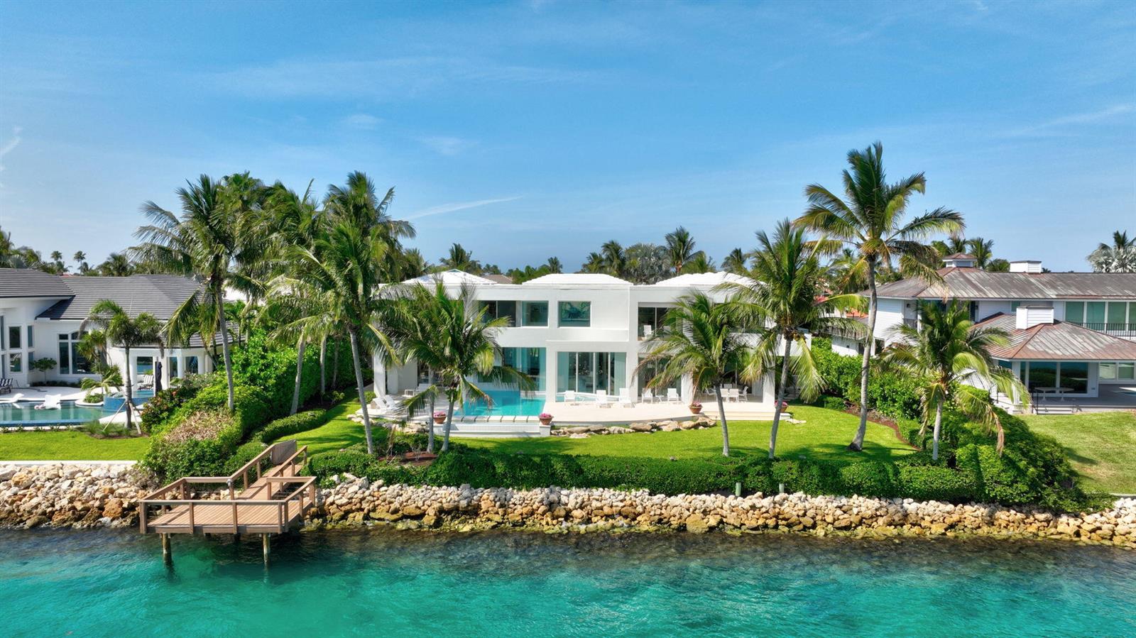 An aerial view of a white two-story waterfront house with a pool and palm trees — 7034 SE Harbor Circle, Stuart FL 34996, STUART, FL