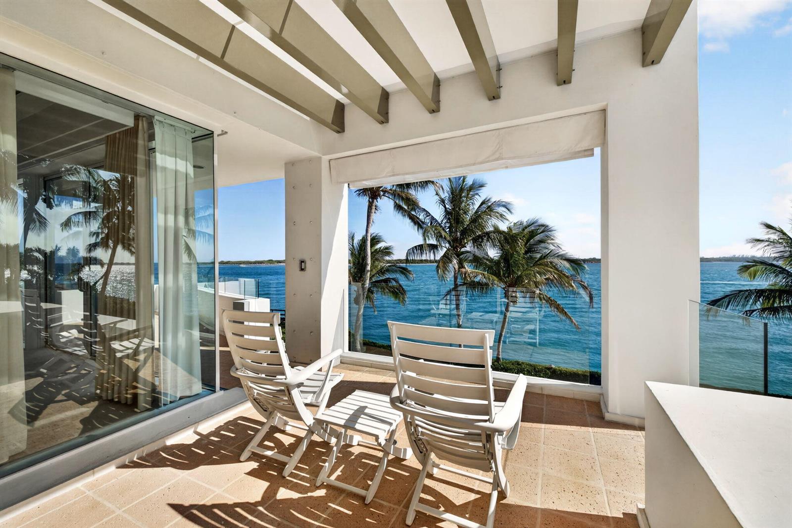 A covered patio with two white chairs overlooks the ocean and palm trees — 7034 SE Harbor Circle, Stuart FL 34996, STUART, FL