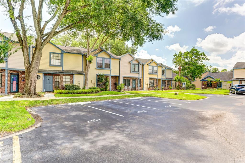 A row of two-story townhomes with yellow siding sits behind a paved parking lot — 2901 WAREHAM COURT, CASSELBERRY, FL