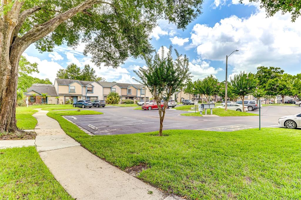 A paved parking lot sits in front of multi-story townhomes surrounded by green lawns and trees — 2901 WAREHAM COURT, CASSELBERRY, FL