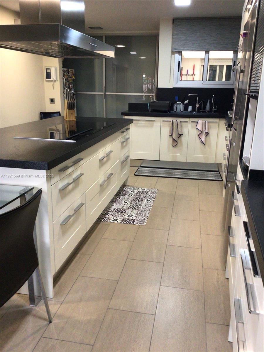 A modern kitchen features a central island with a cooktop, white cabinetry, and dark countertops — 17 Canonge Domenech, PA 17310, PA