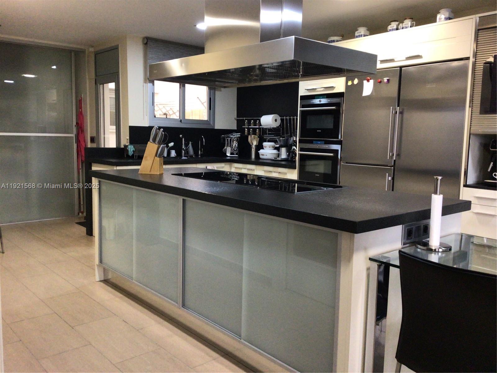 A modern kitchen features a large island with a black countertop and frosted glass cabinets — 17 Canonge Domenech, PA 17310, PA