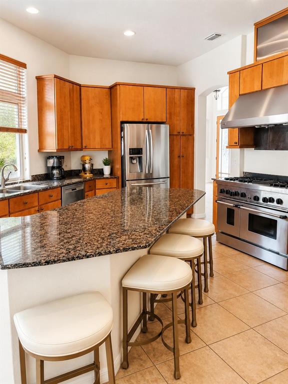 A kitchen features wood cabinets, granite countertops, stainless steel appliances, and three bar stools — 301 SEMINOLE WOODS BOULEVARD, GENEVA, FL