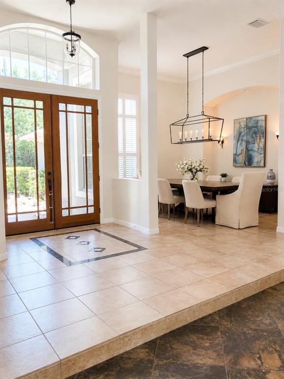 An entryway with tiled floors leads to a dining area featuring a rectangular chandelier — 301 SEMINOLE WOODS BOULEVARD, GENEVA, FL