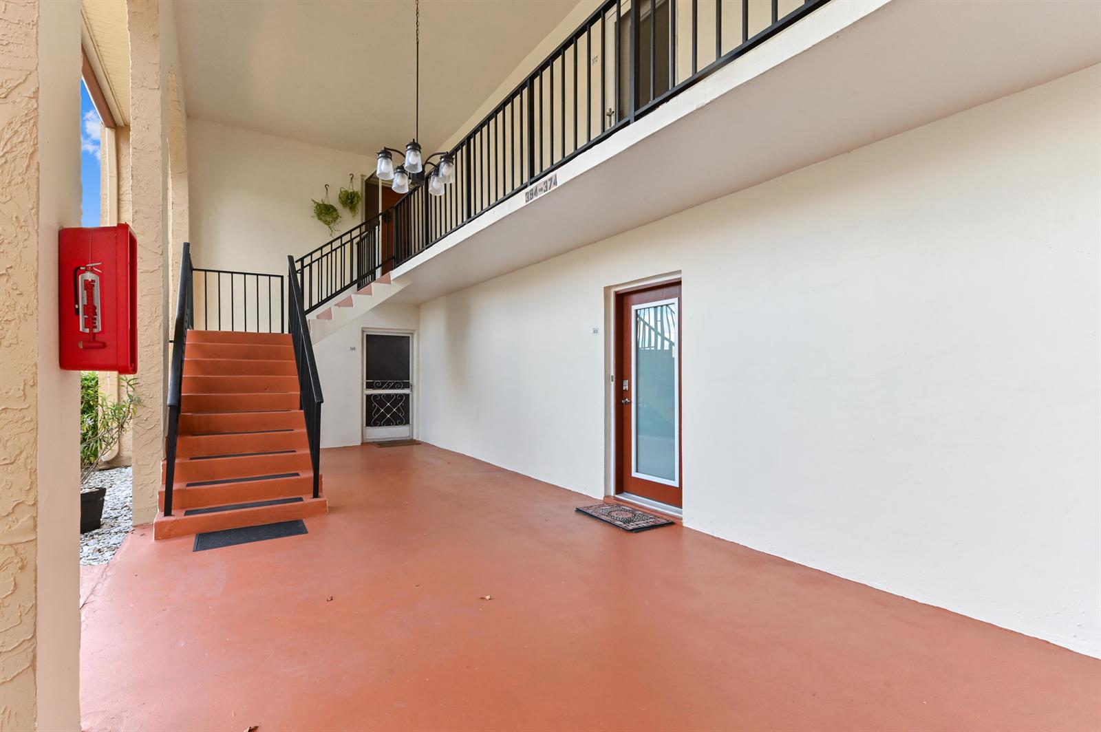 An outdoor stairwell leads to a second-floor balcony with a chandelier and two doors — 368 Lake Frances Drive, West Palm Beach FL 33411, WEST PALM BEACH, FL