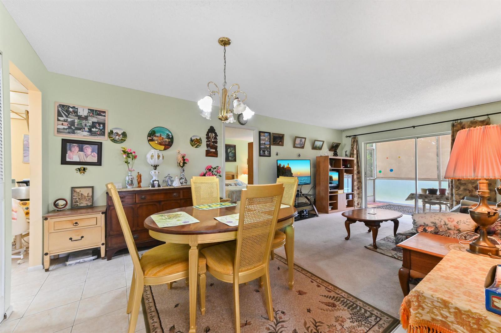 A dining area with a wooden table and chairs sits adjacent to a carpeted living room — 368 Lake Frances Drive, West Palm Beach FL 33411, WEST PALM BEACH, FL