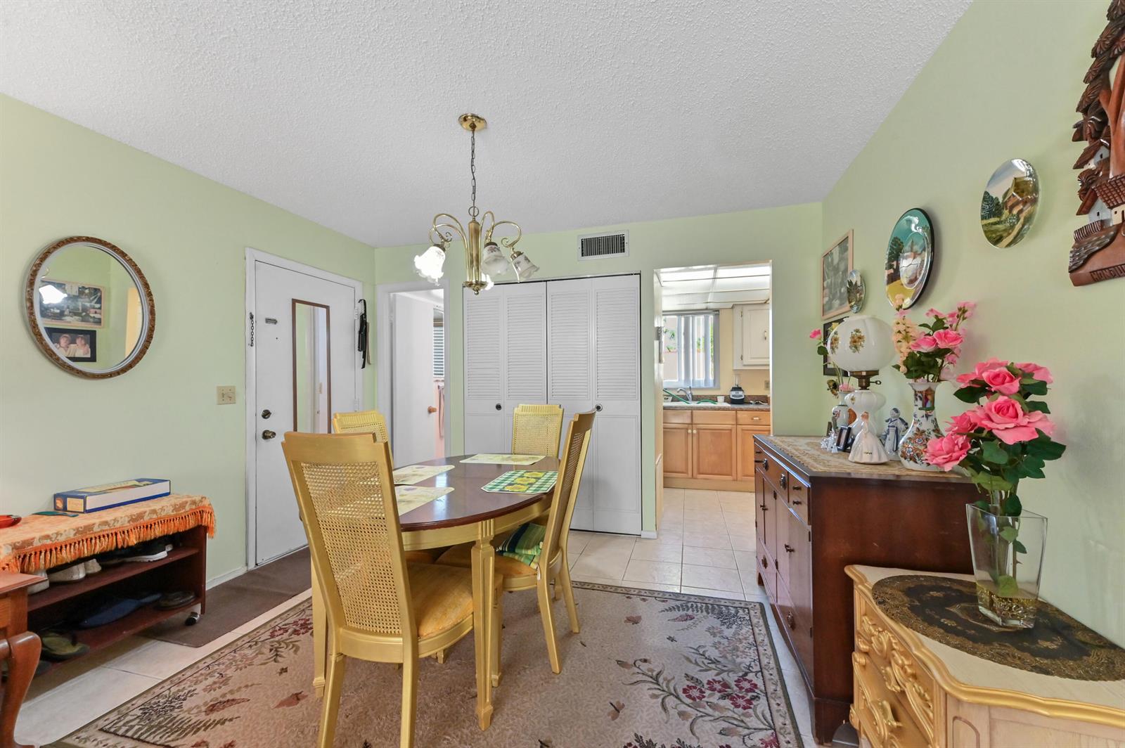 A dining room with light green walls, a wooden table, and a view into the kitchen — 368 Lake Frances Drive, West Palm Beach FL 33411, WEST PALM BEACH, FL