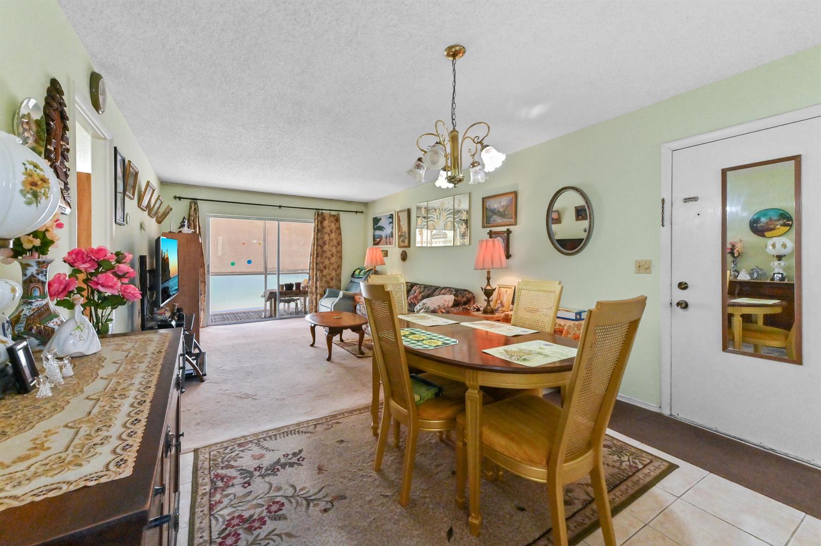 A dining area with a wooden table and chairs sits adjacent to a carpeted living room — 368 Lake Frances Drive, West Palm Beach FL 33411, WEST PALM BEACH, FL