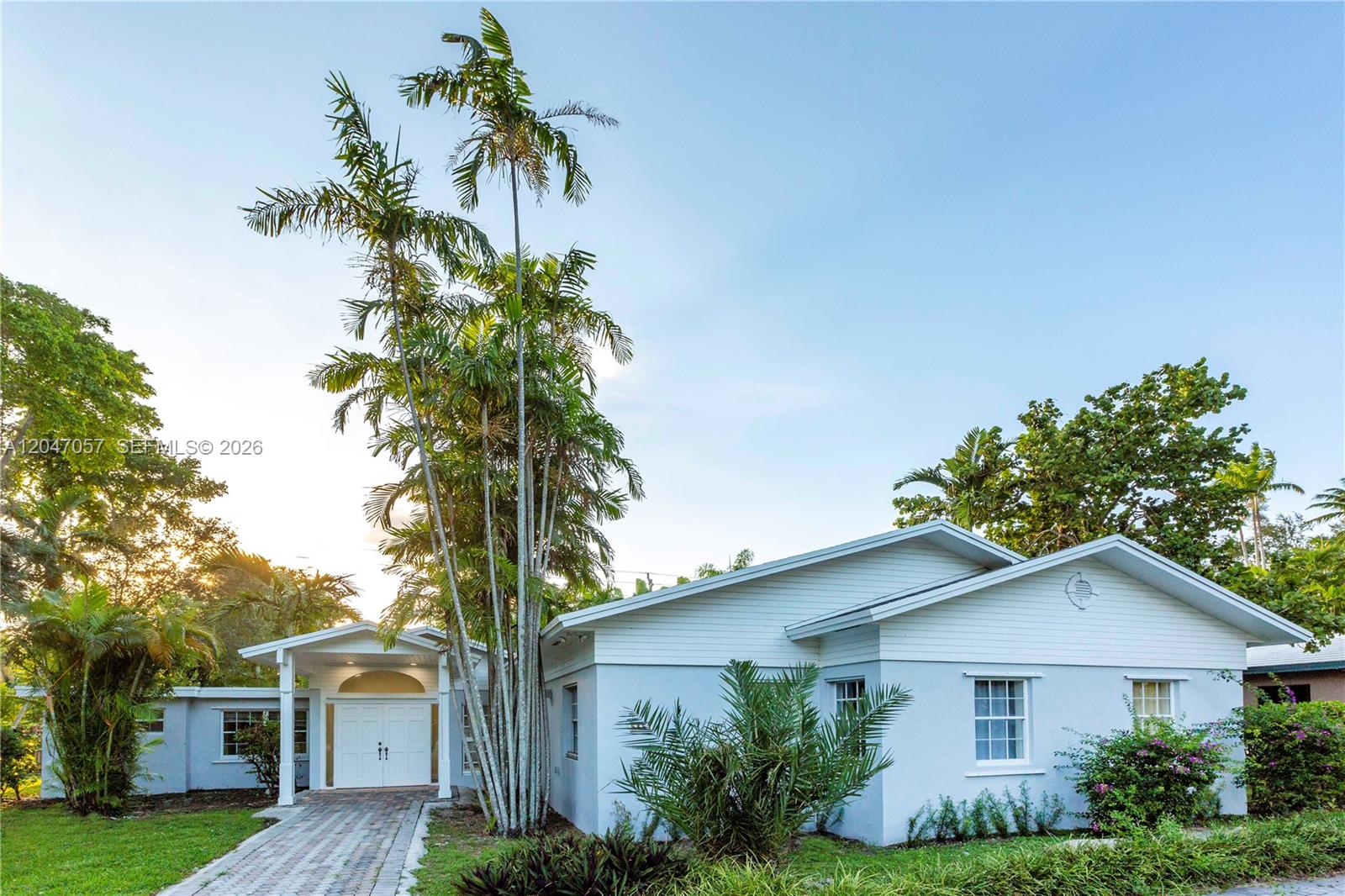 A light blue single-story house features a paved walkway, white double doors, and palm trees — 5451 SW 80th St, Miami FL 33143, MIAMI, FL