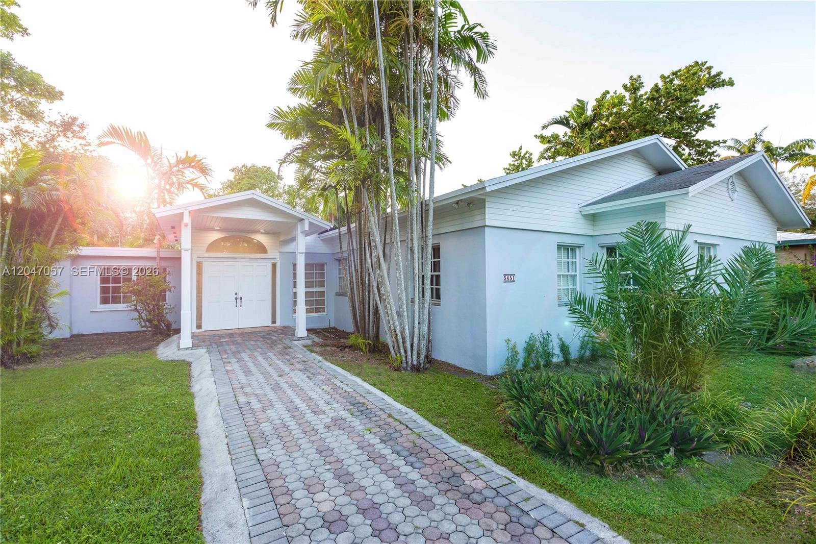A light blue house features a paved walkway leading to a covered white double-door entrance — 5451 SW 80th St, Miami FL 33143, MIAMI, FL