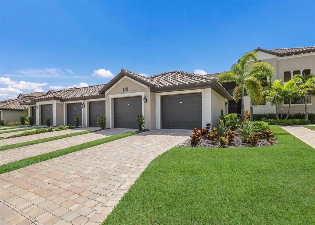 A row of attached single-story homes with brown garage doors and paved driveways — 5710 PALMER CIRCLE UNIT 202, BRADENTON, FL