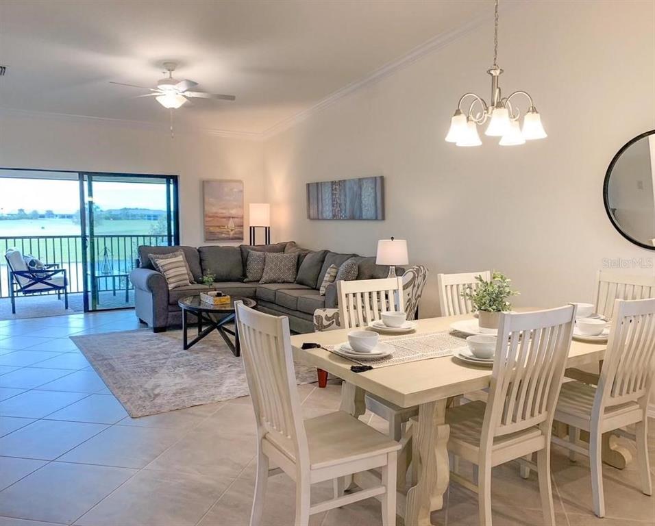 An open-concept dining and living area features a sectional sofa, dining table, and balcony view — 5710 PALMER CIRCLE UNIT 202, BRADENTON, FL