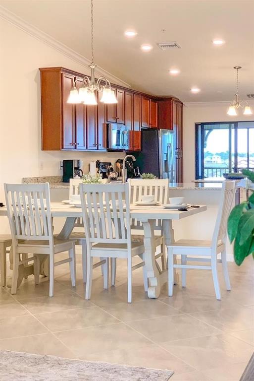 A dining area with a white table and chairs sits before a kitchen with wood cabinets — 5710 PALMER CIRCLE UNIT 202, BRADENTON, FL